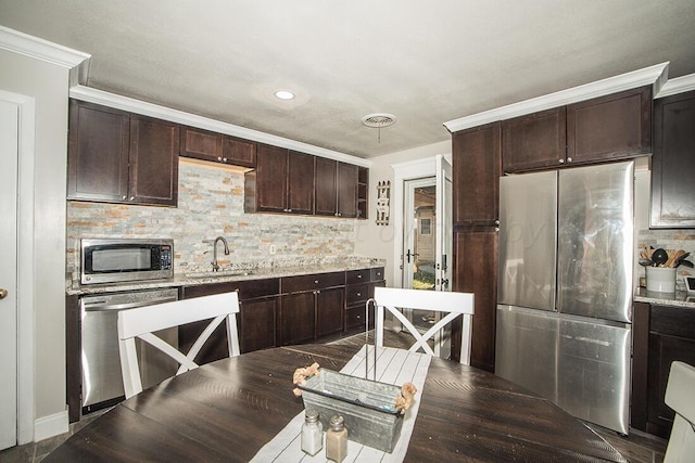 kitchen with stainless steel appliances, dark brown cabinets, a sink, and visible vents