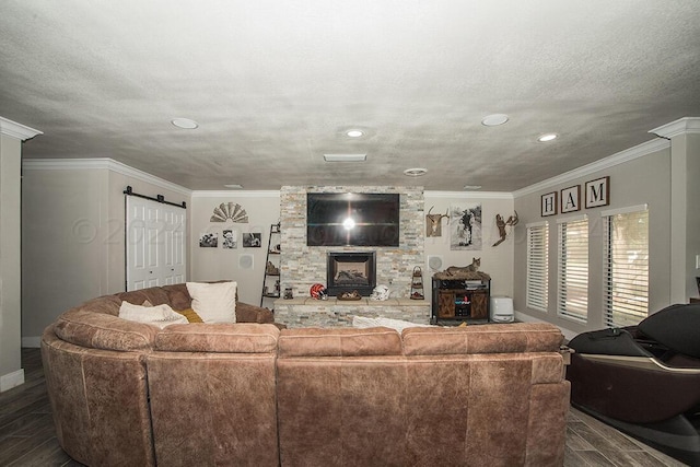 living area featuring dark wood-type flooring, ornamental molding, a textured ceiling, and a barn door