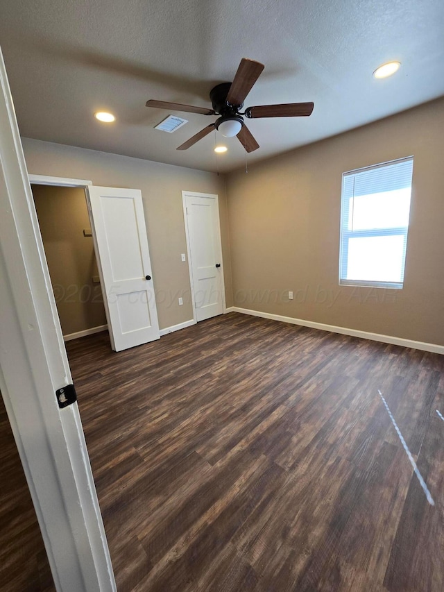 unfurnished bedroom featuring ceiling fan, dark wood-type flooring, and a textured ceiling