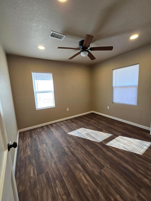 spare room with ceiling fan, a textured ceiling, and dark hardwood / wood-style flooring