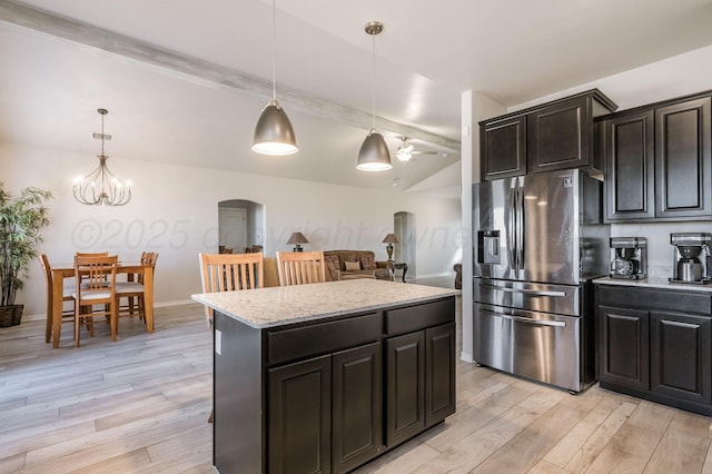 kitchen featuring arched walkways, stainless steel fridge, decorative light fixtures, and light wood-style floors