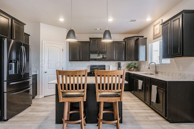 kitchen featuring light stone counters, visible vents, a sink, and black appliances