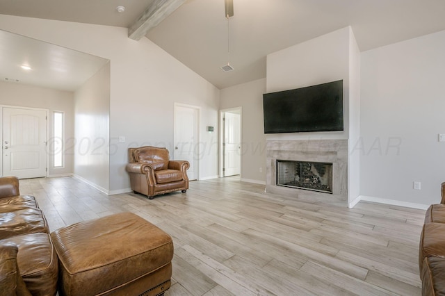 living room featuring light wood finished floors, a tiled fireplace, visible vents, and beamed ceiling