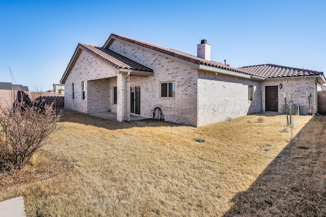 back of property featuring a tiled roof, a lawn, a chimney, and fence