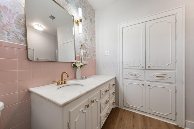 bathroom with hardwood / wood-style floors, vanity, and tile walls