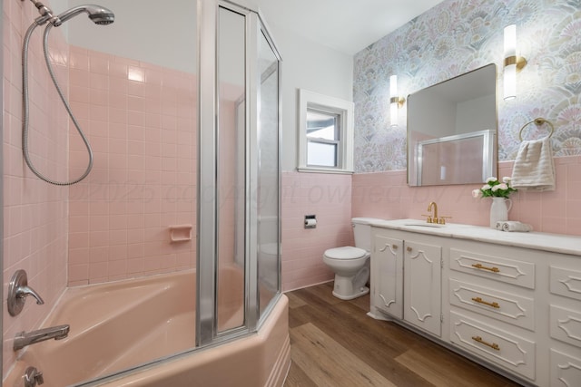 full bathroom with enclosed tub / shower combo, tile walls, vanity, wood-type flooring, and toilet