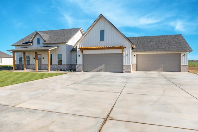 modern farmhouse with driveway, board and batten siding, a shingled roof, an attached garage, and a front yard