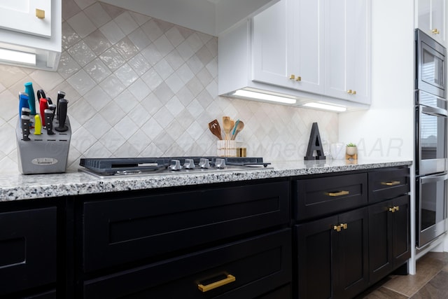 kitchen featuring white cabinets, light stone countertops, appliances with stainless steel finishes, and tasteful backsplash