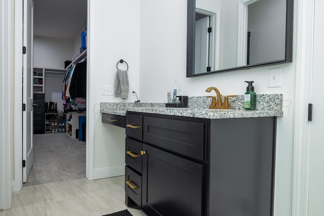 full bath with a spacious closet, baseboards, and vanity