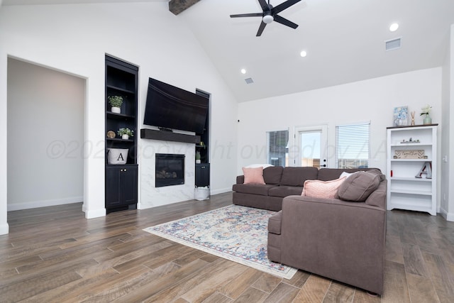 living room with a high end fireplace, visible vents, a ceiling fan, beam ceiling, and high vaulted ceiling