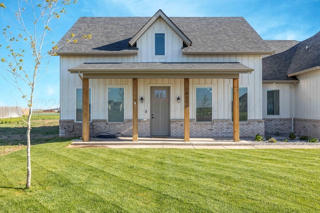 view of front of home with board and batten siding, roof with shingles, and a front lawn