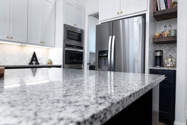 kitchen with light stone counters, tasteful backsplash, open shelves, and stainless steel appliances