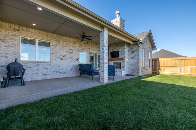 exterior space with fence, a large fireplace, and ceiling fan
