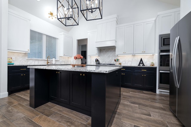 kitchen featuring high vaulted ceiling, a center island, dark cabinetry, white cabinets, and appliances with stainless steel finishes
