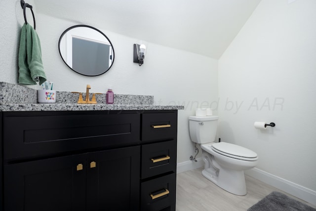 bathroom featuring toilet, baseboards, lofted ceiling, wood finished floors, and vanity
