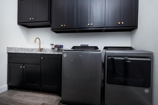 washroom with baseboards, a sink, washer and clothes dryer, and cabinet space
