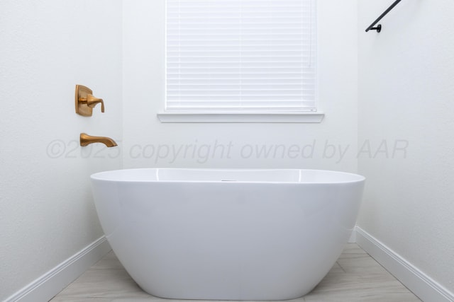 bathroom featuring a freestanding bath and baseboards
