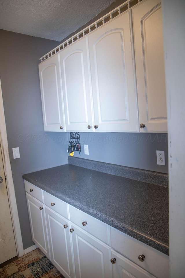 1403 Charles Ave, Panhandle, TX 79068 - kitchen with dark countertops, white cabinets, and a textured ceiling