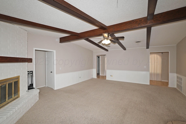 3519 Rutson Dr, Amarillo, TX 79109 - unfurnished living room featuring light colored carpet, ceiling fan, wainscoting, a fireplace, and a textured ceiling