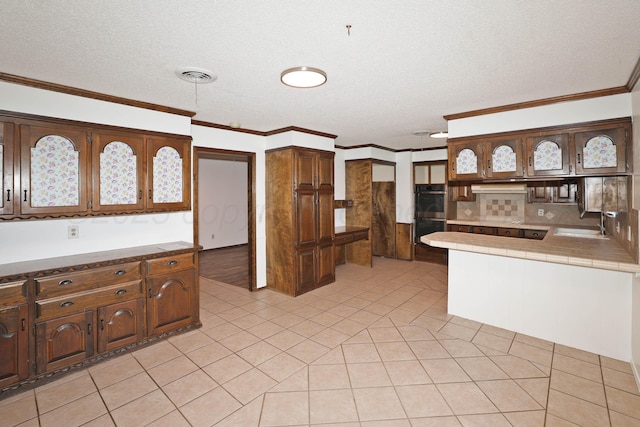 3519 Rutson Dr, Amarillo, TX 79109 - kitchen featuring tile counters, tasteful backsplash, stainless steel double oven, a textured ceiling, and a sink