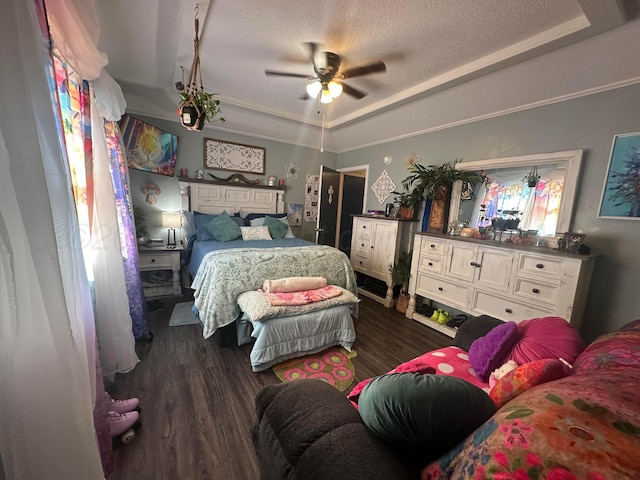 bedroom with a raised ceiling, ceiling fan, dark wood-type flooring, and a textured ceiling