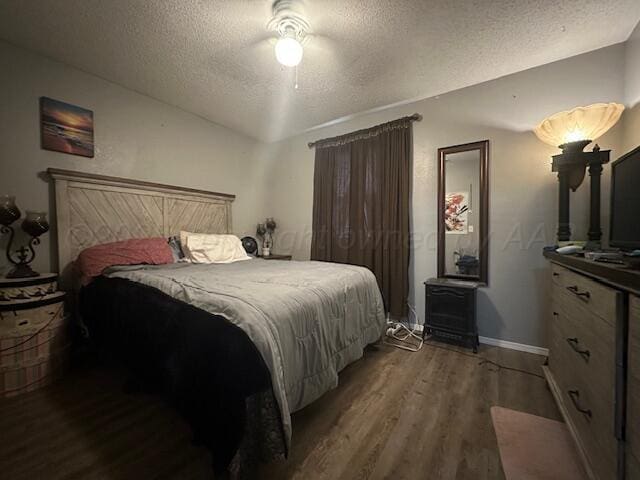 bedroom featuring dark wood-type flooring, ceiling fan, and a textured ceiling