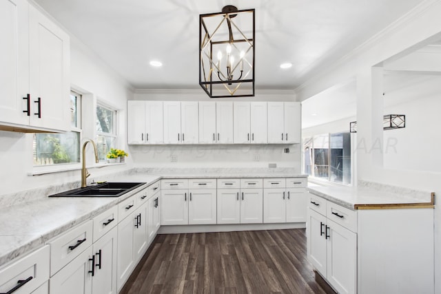 kitchen with dark wood-type flooring, white cabinets, hanging light fixtures, sink, and ornamental molding