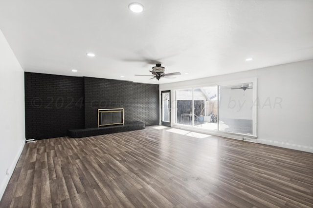 unfurnished living room featuring ceiling fan, dark hardwood / wood-style floors, and a brick fireplace