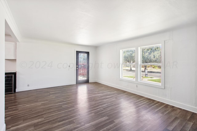 unfurnished living room featuring wine cooler, ornamental molding, and dark hardwood / wood-style floors