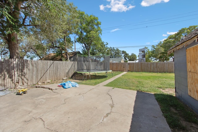 view of yard with a trampoline and a patio