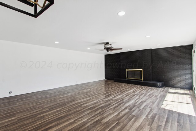 unfurnished living room featuring brick wall, hardwood / wood-style flooring, ceiling fan, and a fireplace