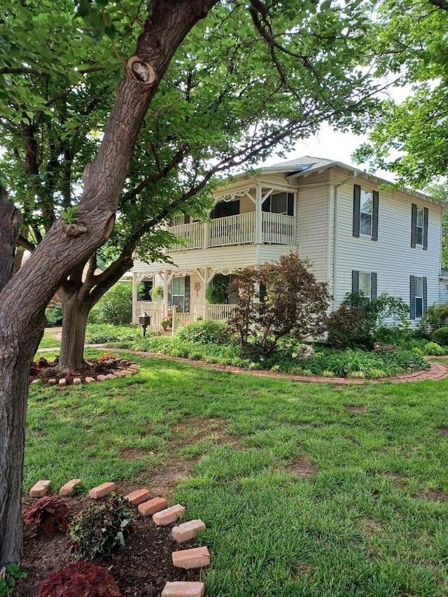 view of side of home featuring a lawn and a balcony
