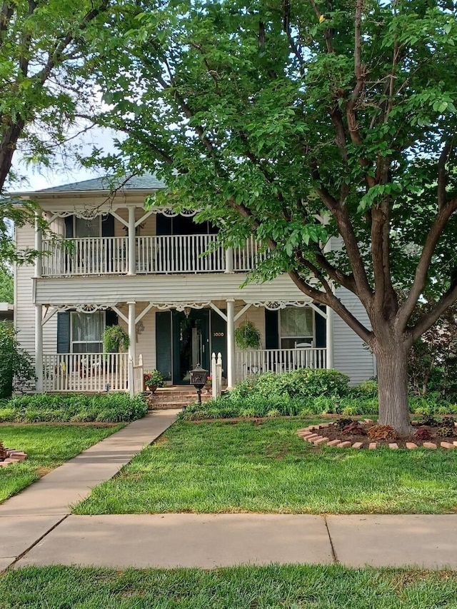 view of front of home featuring a porch, a balcony, and a front lawn