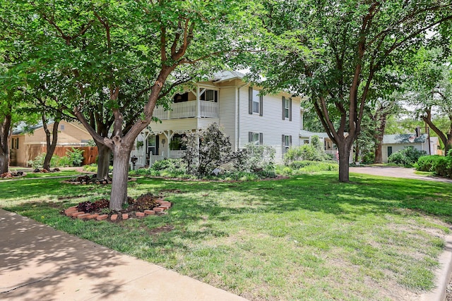 view of front of house featuring a balcony and a front lawn