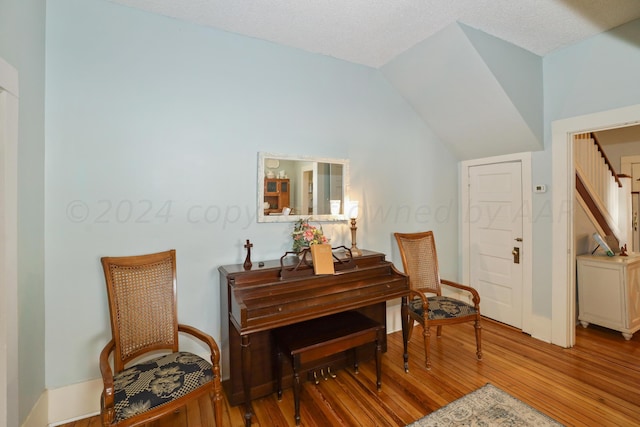 sitting room with wood finished floors and vaulted ceiling