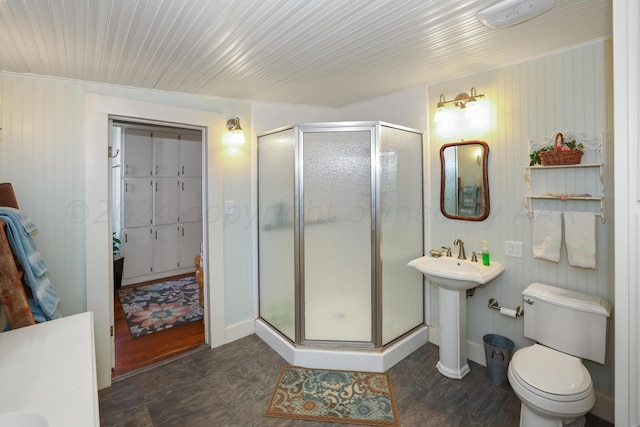full bath with a stall shower, toilet, baseboards, and wood finished floors