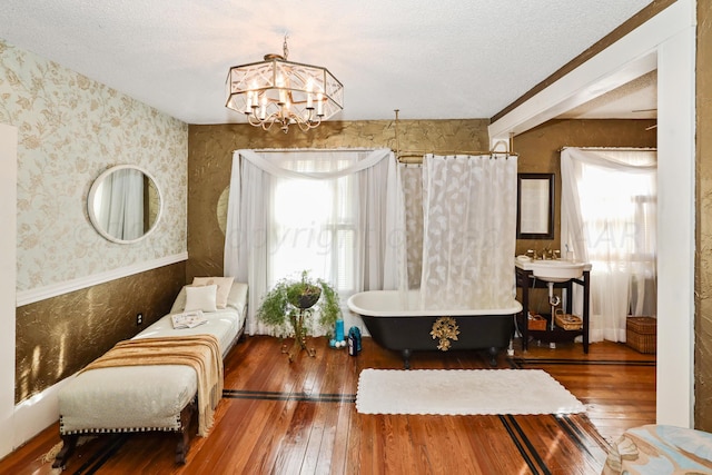 sitting room featuring hardwood / wood-style floors, plenty of natural light, wallpapered walls, a chandelier, and a textured ceiling