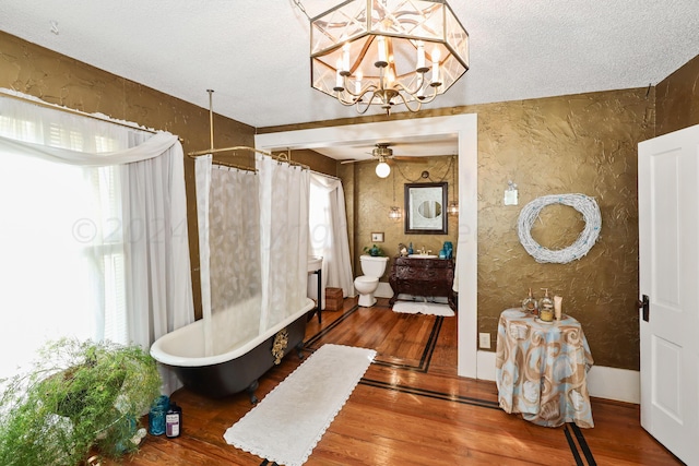 bathroom with wood finished floors, curtained shower, a ceiling fan, a textured wall, and a tub to relax in