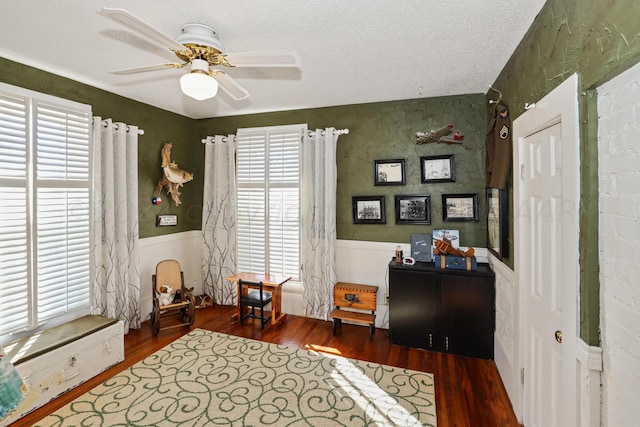 office space featuring wood finished floors, ceiling fan, a wainscoted wall, and a textured ceiling