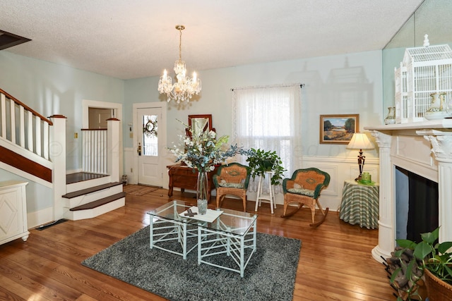 living area with stairs, wood finished floors, and a chandelier