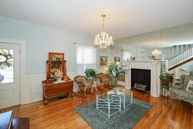 living area featuring a chandelier, hardwood / wood-style flooring, wainscoting, and a fireplace