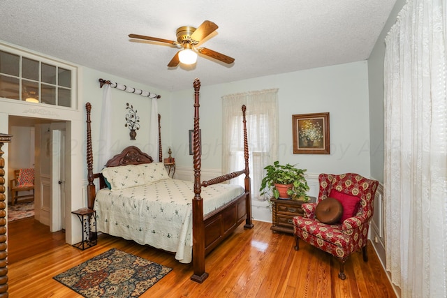 bedroom with hardwood / wood-style floors, a textured ceiling, and ceiling fan