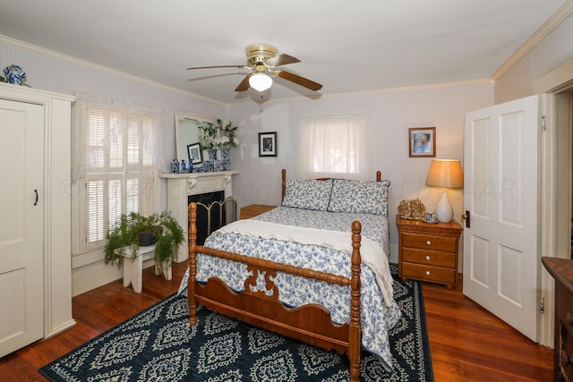 bedroom with dark wood finished floors, crown molding, ceiling fan, and a fireplace