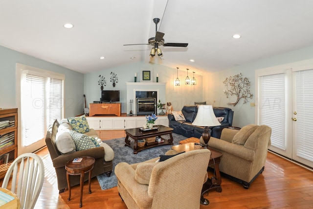 living room with vaulted ceiling, ceiling fan, wood finished floors, a glass covered fireplace, and recessed lighting