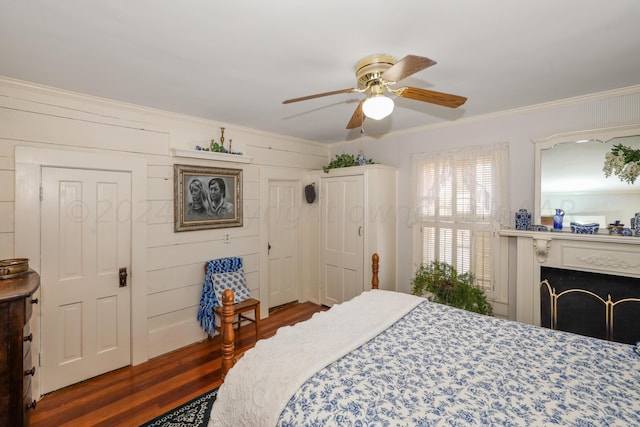 bedroom with wood finished floors, ornamental molding, ceiling fan, and a fireplace