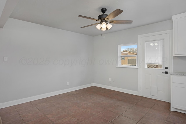 unfurnished room with ceiling fan and baseboards