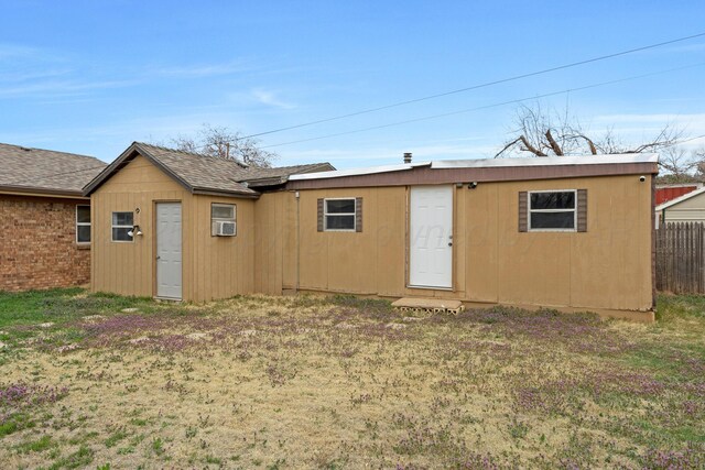 rear view of property with fence and roof with shingles