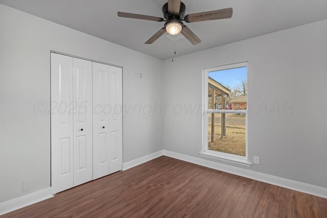 unfurnished bedroom featuring dark wood-type flooring, baseboards, a closet, and ceiling fan