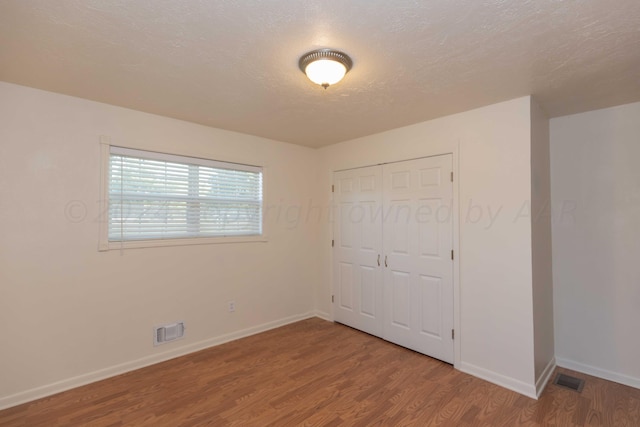 unfurnished bedroom with a closet, light wood-style flooring, visible vents, and baseboards