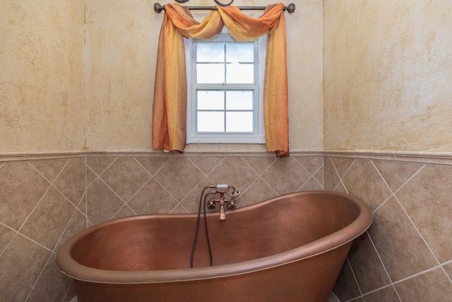 bathroom featuring a soaking tub and tile walls